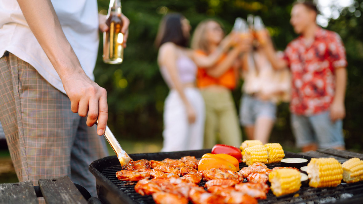 Мужчина жарит шашлык и пьет пиво