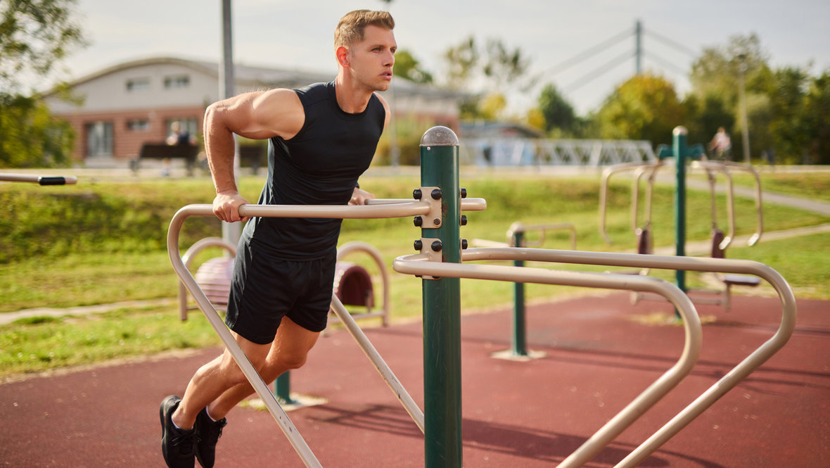 Юноша отжимается на брусьях