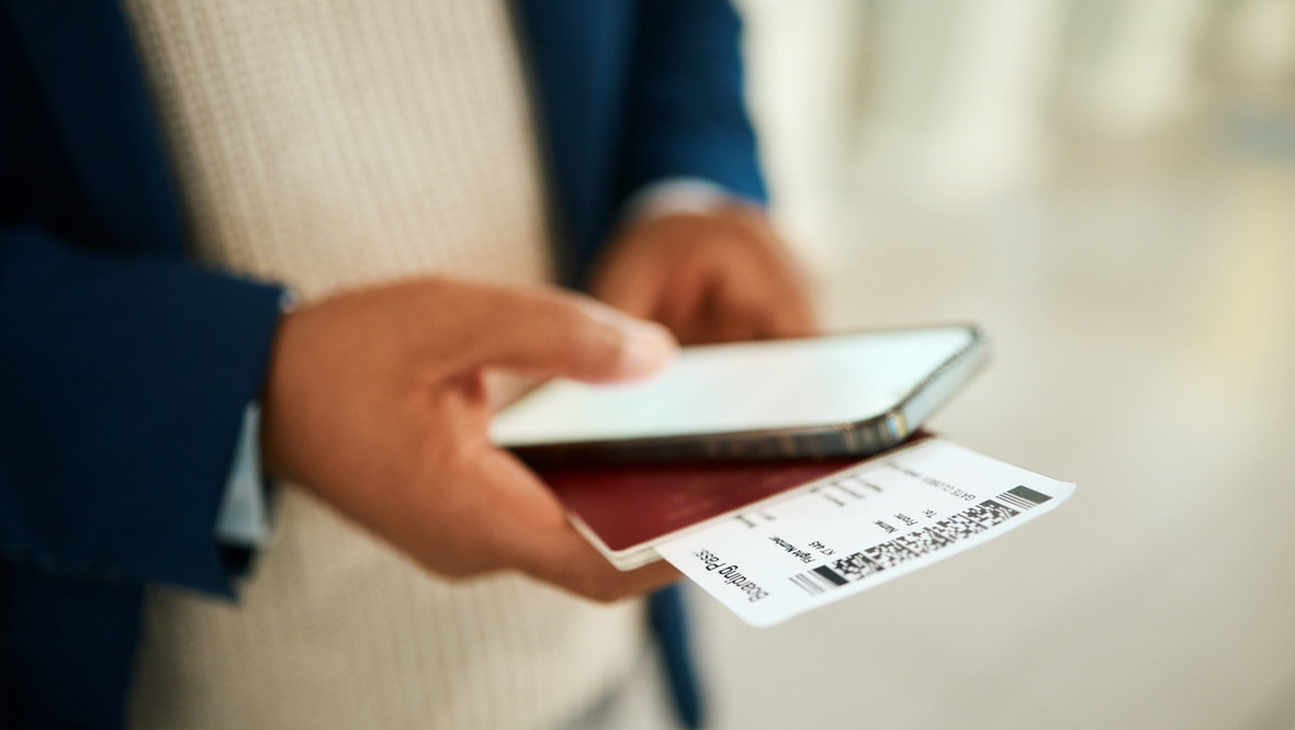 Мужчина держит в руках телефон и авиабилеты