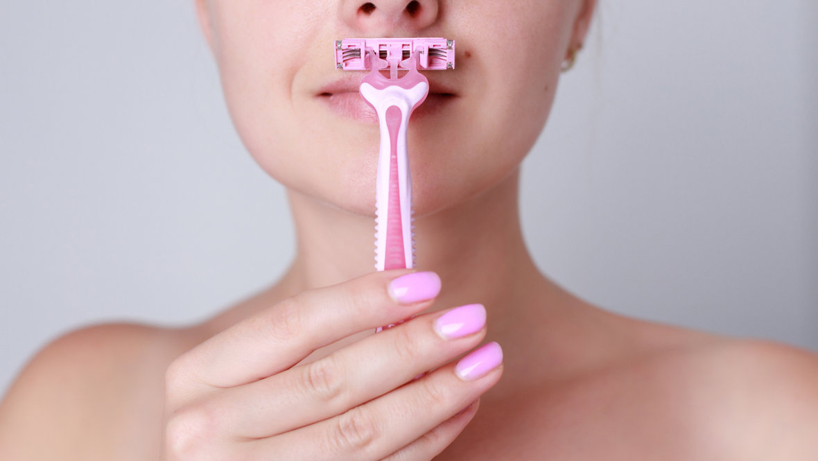 Девушка бреет лицо.