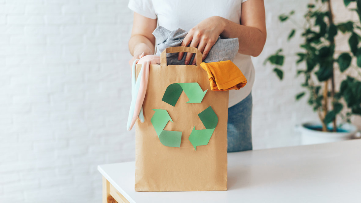 Девушка складывает старую одежду на переработку