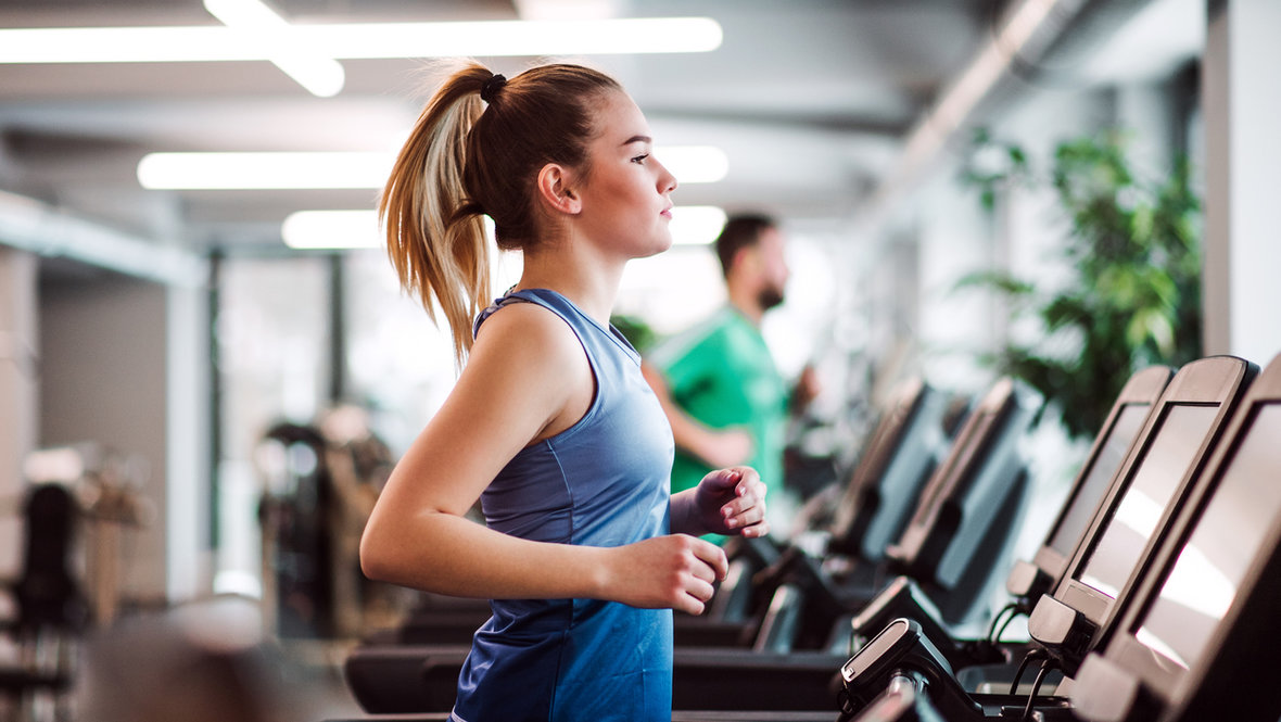 Девушка бегает по беговой дорожке