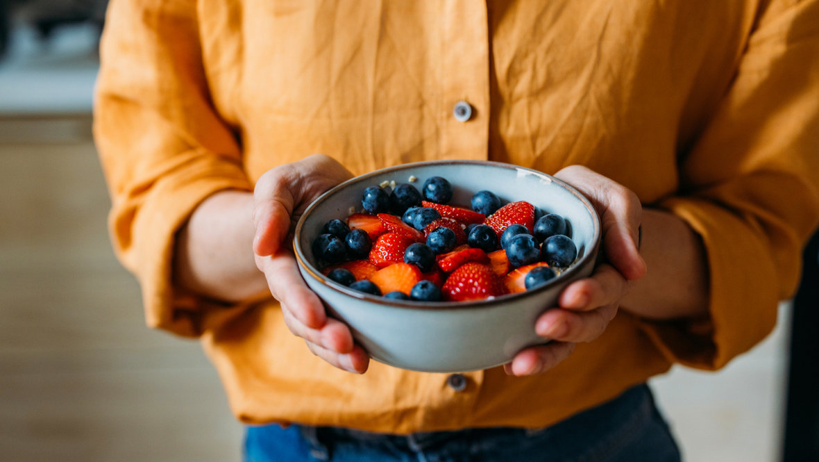 Ягоды в тарелке в руках девушки