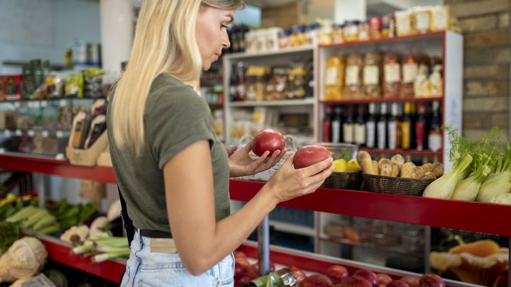 Девушка выбирает овощи в магазине