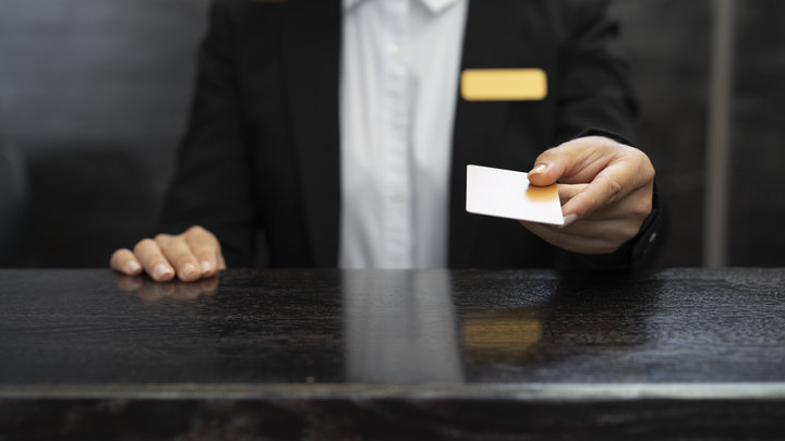 Девушка выдает карту для заселения в отель