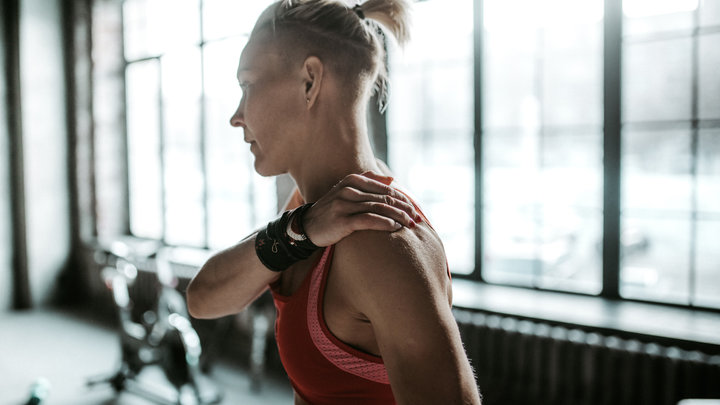 Мужчина трогает плечо на тренировке