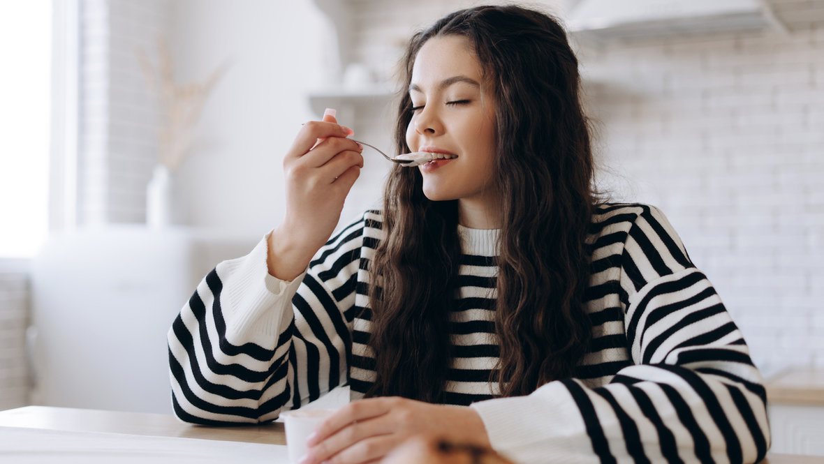 Девушка ест йогурт