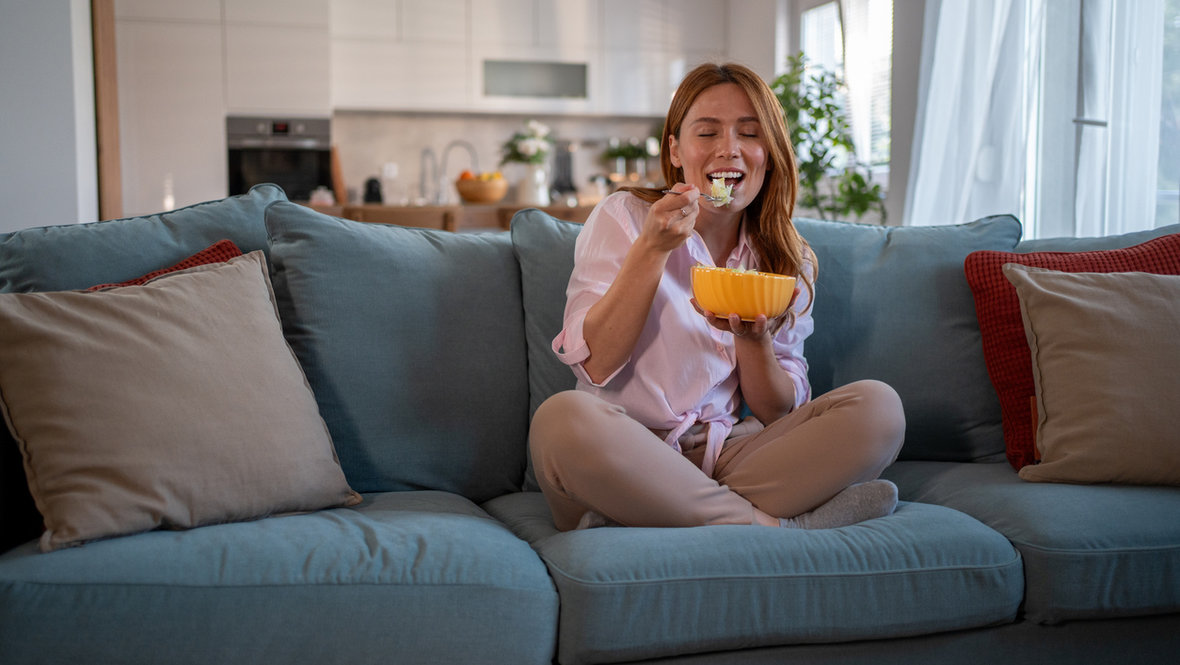 Девушка ест на диване