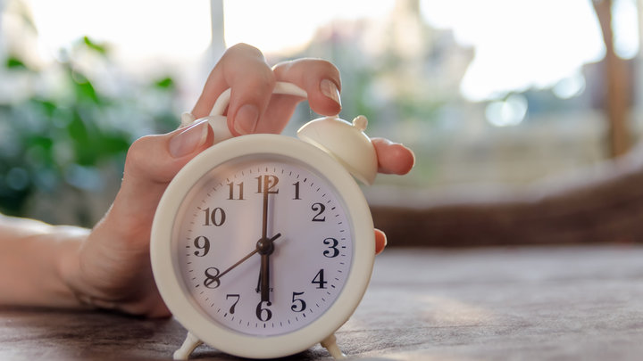 Женщина пытается выключить будильник