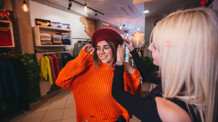 Девушка мерит берет в магазине