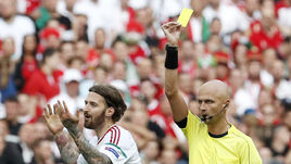 Сергей КАРАСЕВ показывает карточку защитнику сборной Венгрии Тамашу КАДАРУ.